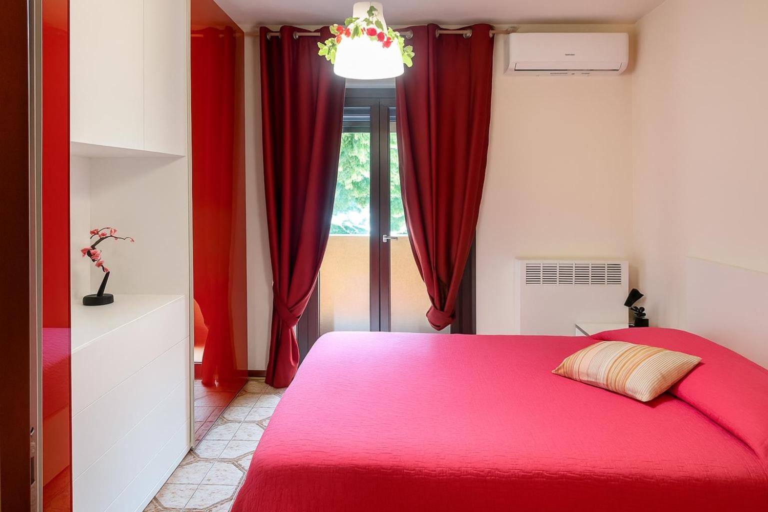 La camera matrimoniale con copriletto fucsia e tende rosse
