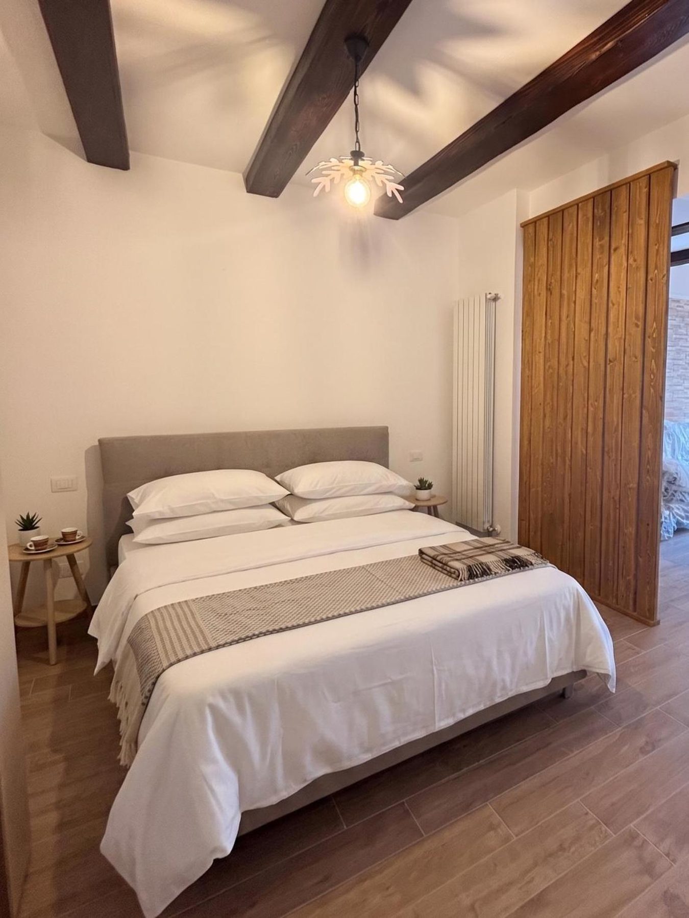 La camera da letto: letto matrimoniale, travi scure e una parete in doghe di legno