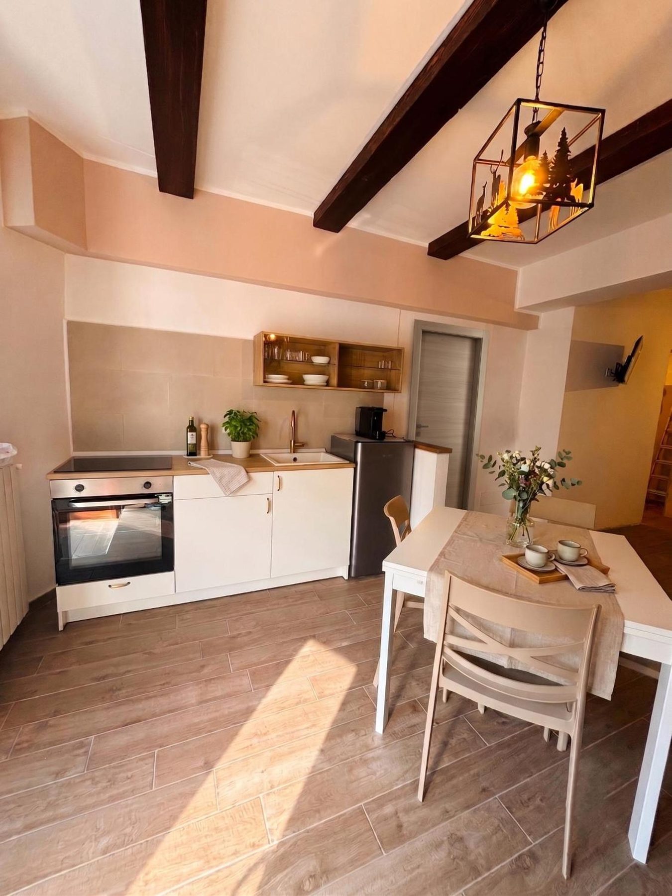 La zona giorno di La Rua: cucina, tavolo e il sole che entra sul pavimento in legno