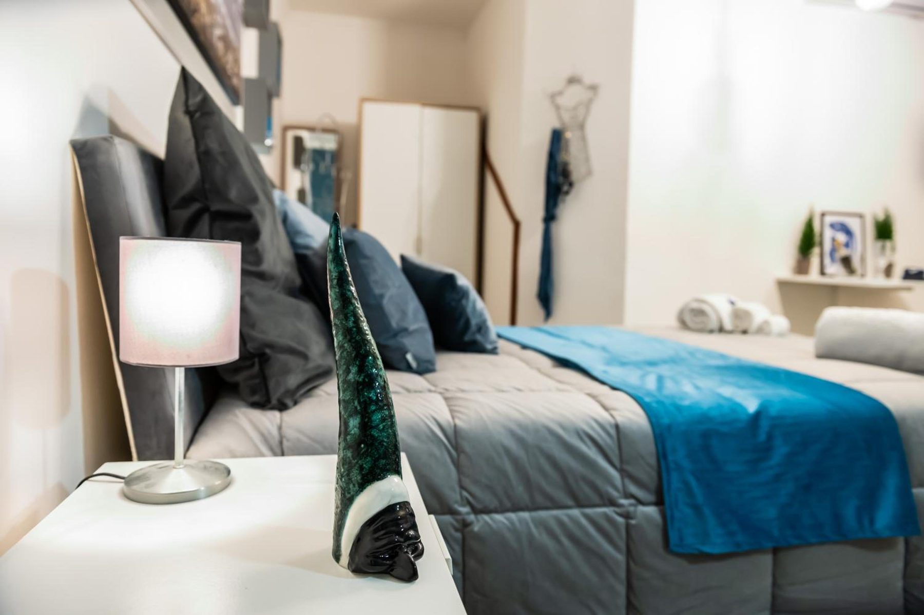 Il letto con i cuscini scuri e la lampada sul comodino