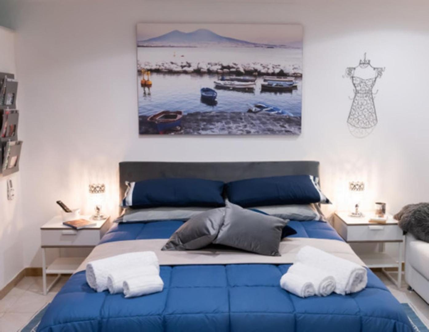 Il letto sotto la tela del Vesuvio, con due lampade da comodino