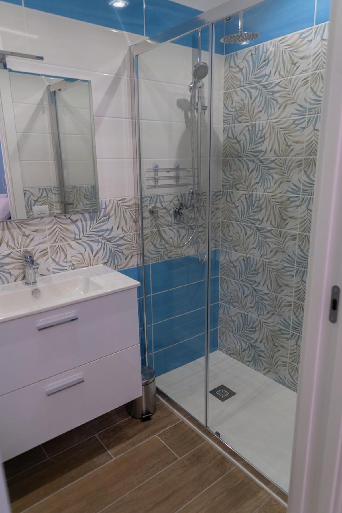 Bagno con doccia in cristallo e piastrelle a foglie